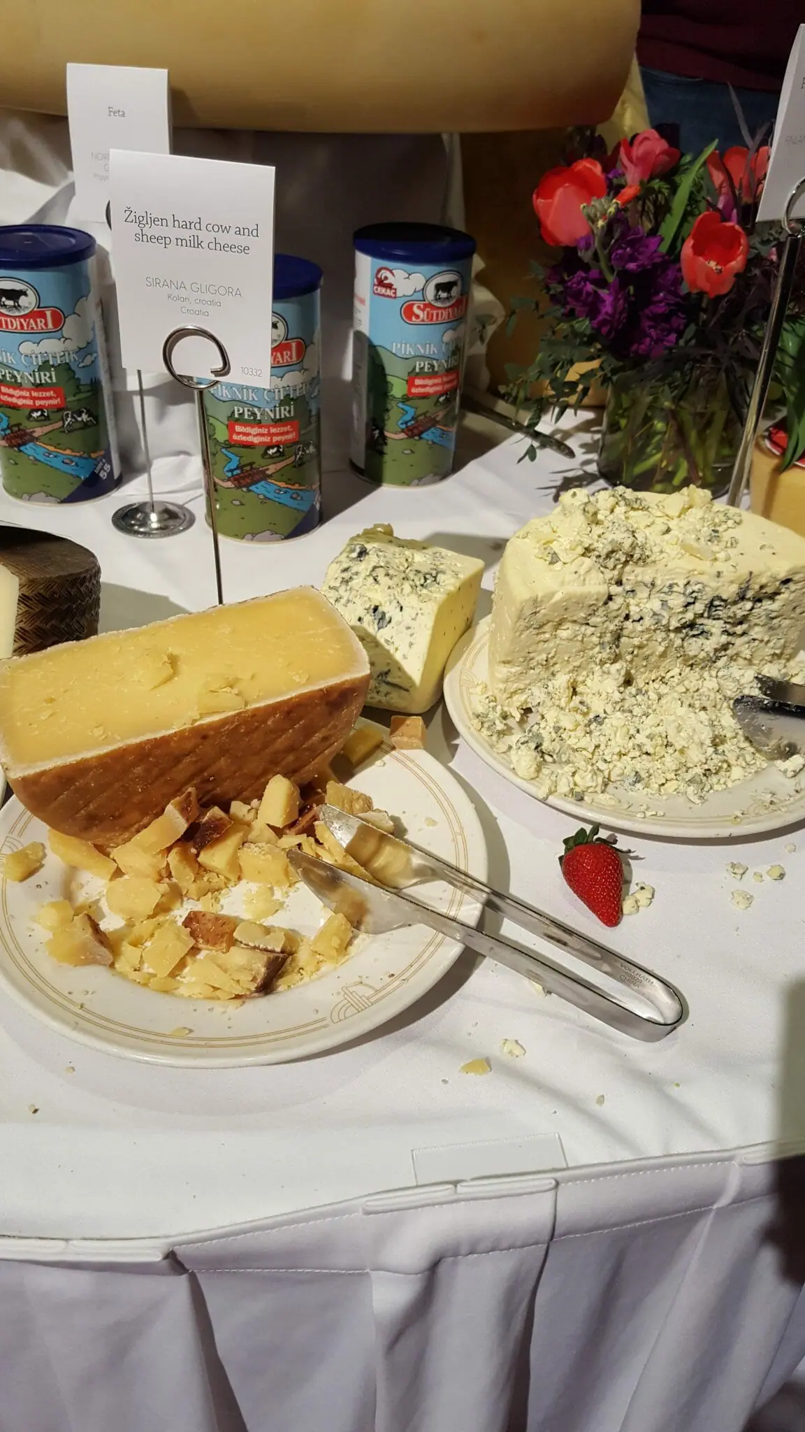 Display table with name cards and tongs by blocks and sample pieces of Blue cheese and other cheese in competition.