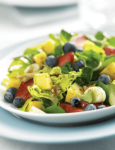 A colorful salad of mixed lettuce greens, strawberries, pineapple chunks, blueberries, and banana slices.
