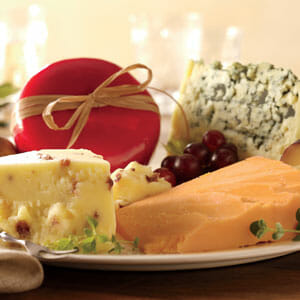 Cheddar, Blue cheese, Cranberry cheese, and Red-wax Gouda cheese tied with a bow, displayed with red grapes.
